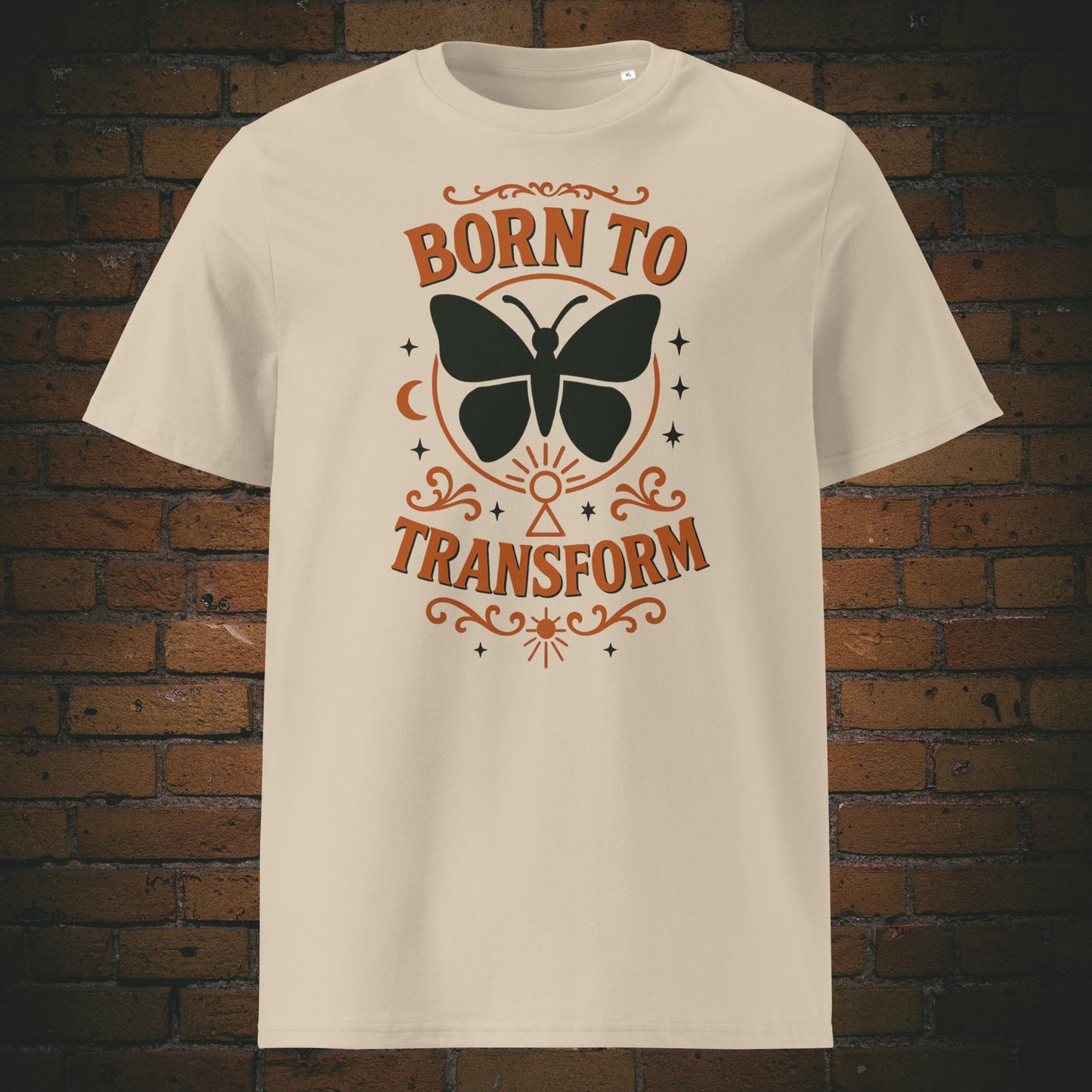 Sandfarben T-Shirt mit Schmetterlingsmotiv und Spruch „Born to Transform“, verziert mit spirituellen Symbolen wie Mond, Sternen und Schlüsselloch – Boho-inspiriertes Design.