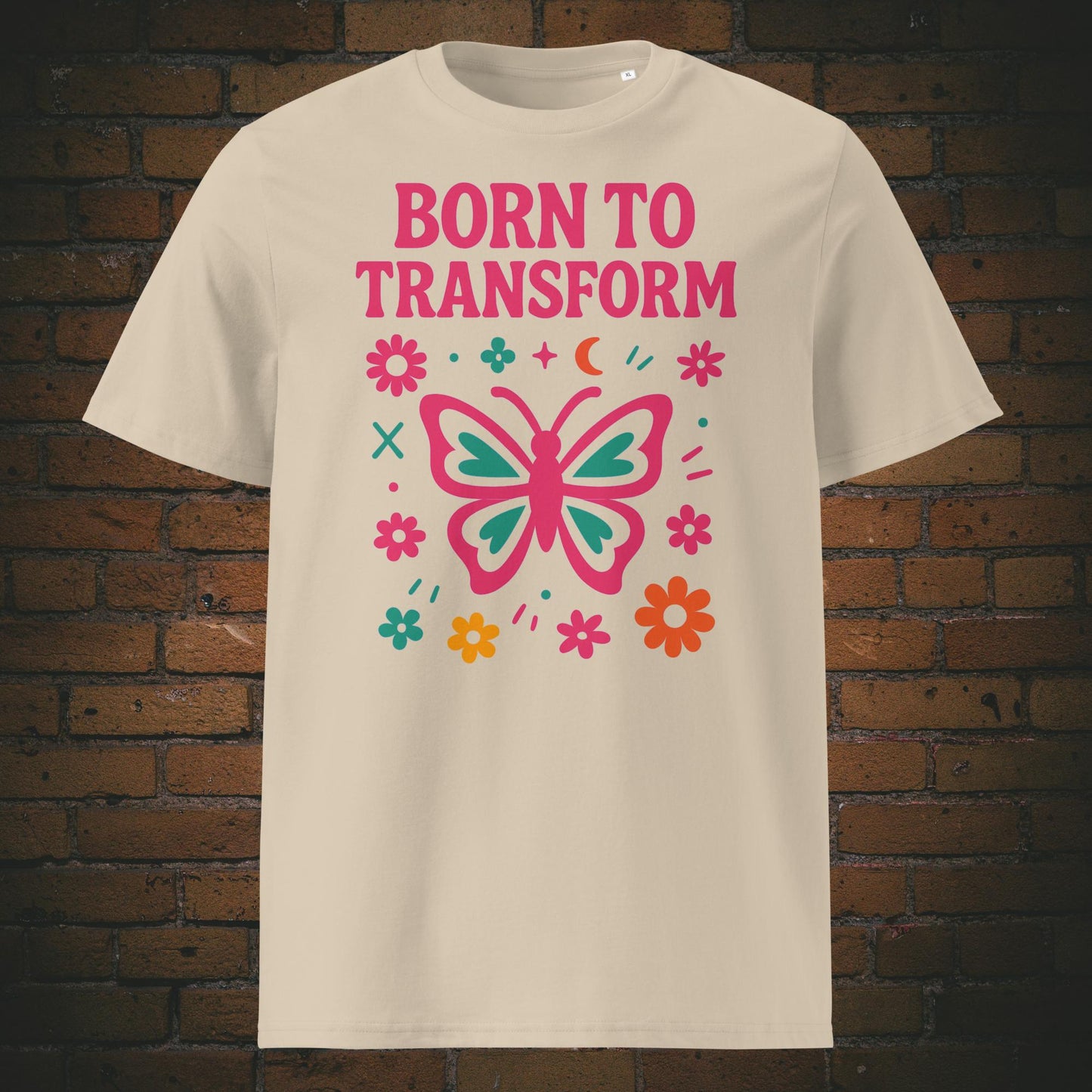 Fröhliches Statement-T-Shirt mit pink-türkisem Schmetterling und floralen Elementen – Symbol für Transformation, Freiheit und positive Energie. Shirtfarbe: Sandfarben