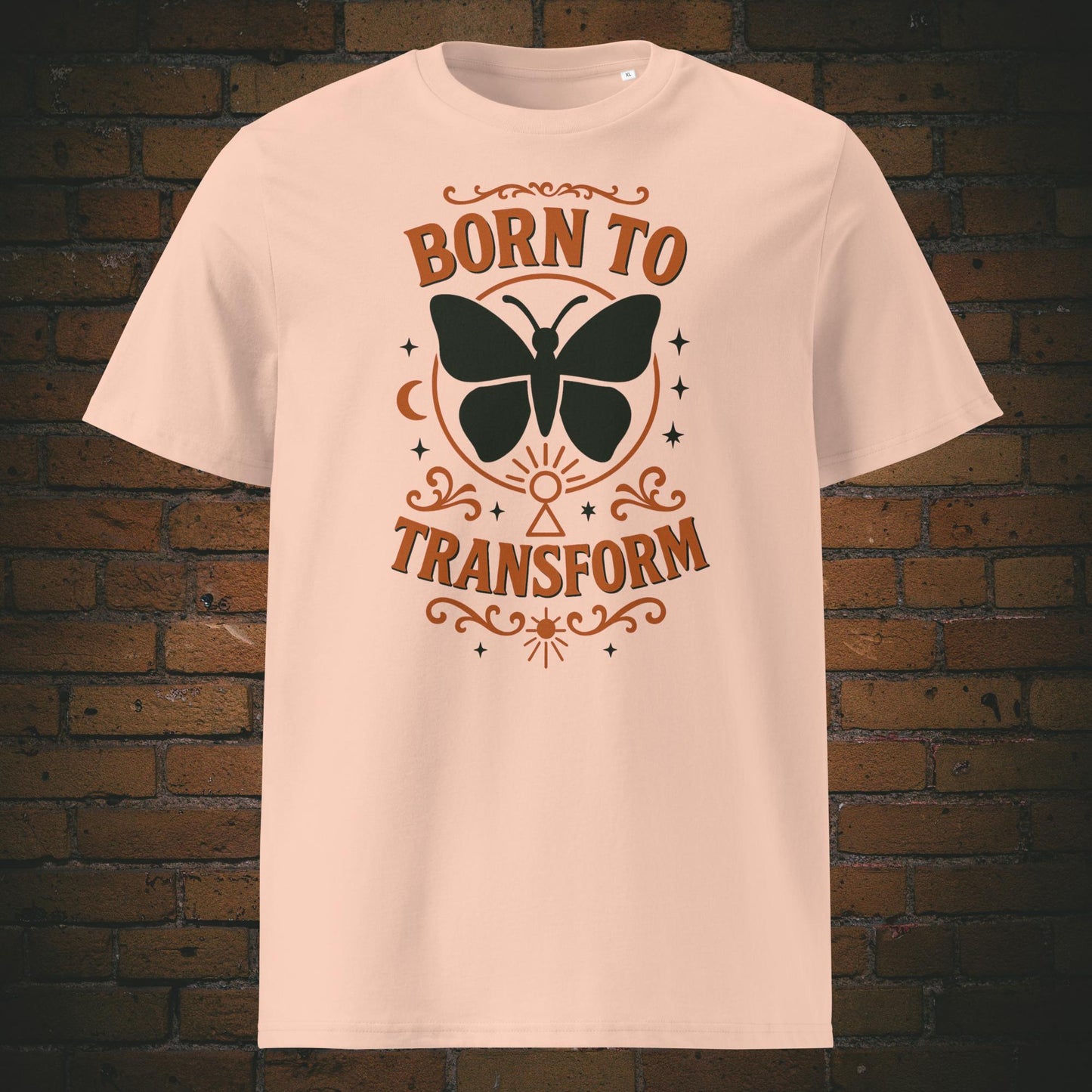 Hellrosa T-Shirt mit Schmetterlingsmotiv und Spruch „Born to Transform“, verziert mit spirituellen Symbolen wie Mond, Sternen und Schlüsselloch – Boho-inspiriertes Design.