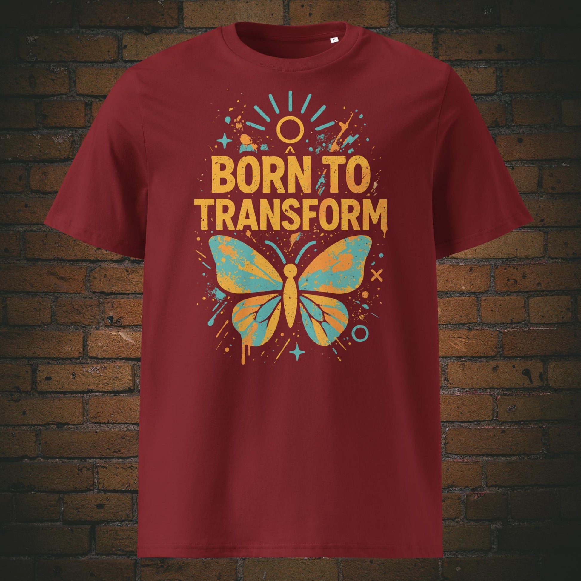 Bordeauxrotes T-Shirt mit buntem Schmetterling und Spruch „Born to Transform“, modernes Graffiti-Design mit Farbspritzern, Sternen und Sonnenstrahlen.